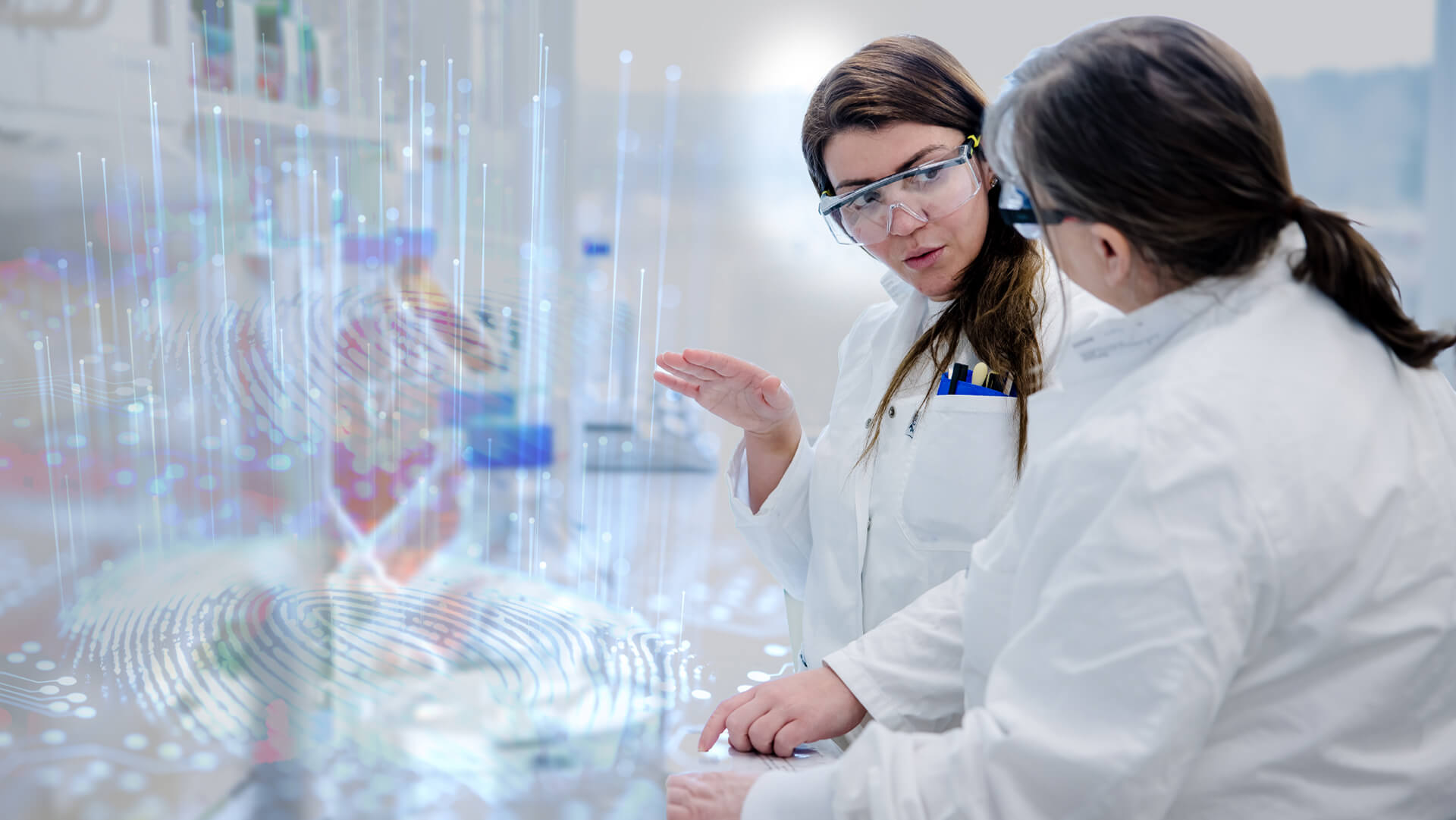 Two scientists in white lab coats and safety goggles discussing digital holograms of fingerprints in a lab.